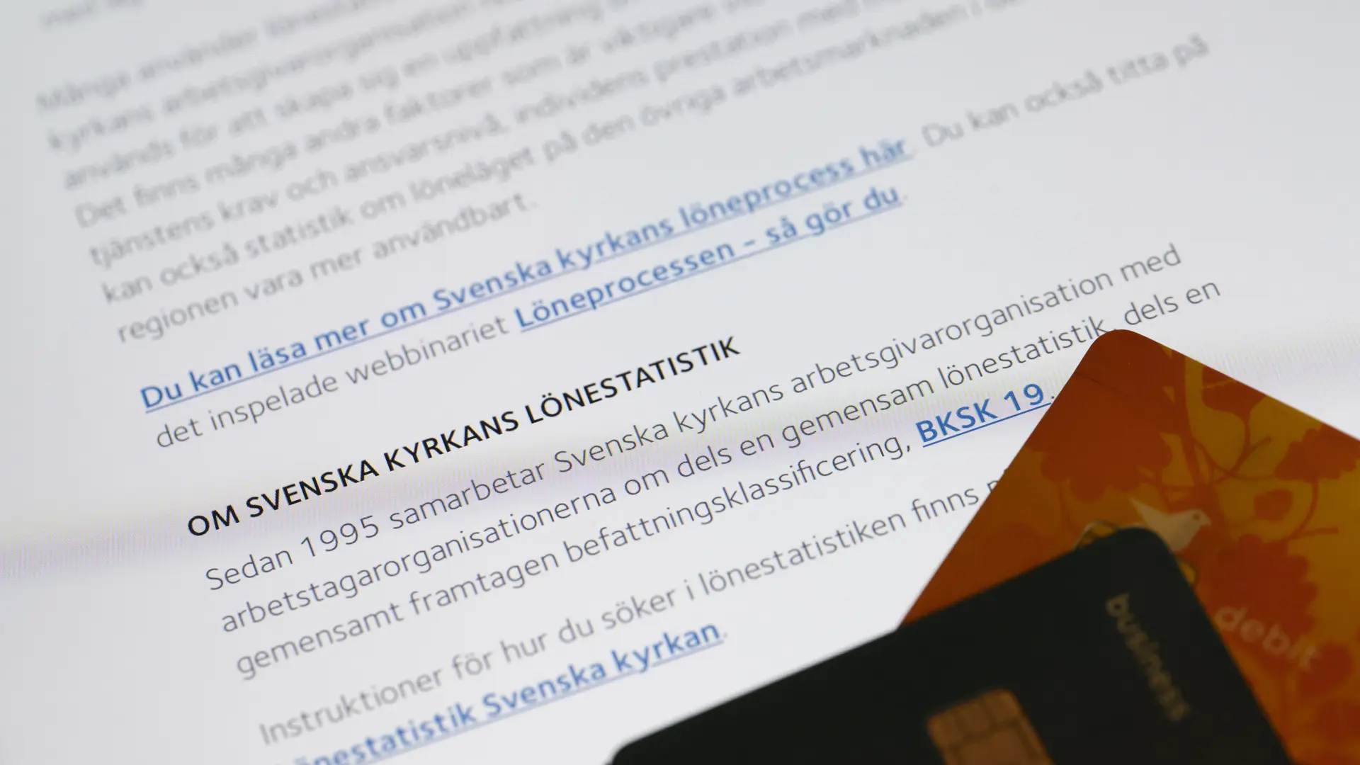 Papper om lönestatistik och två bankkort i förgrunden